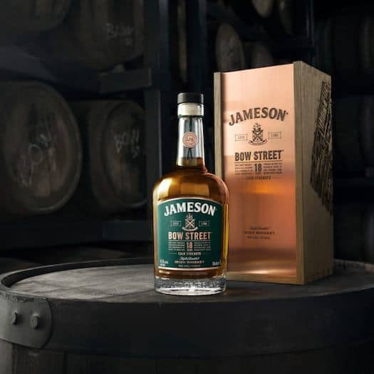A bottle of Jameson 18 year old whiskey on a barrel with barrels in the background