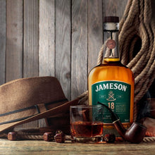 Load image into Gallery viewer, A bottle of Jameson 18 year old whiskey on a wood table with a tumbler and some dices rolling on the table