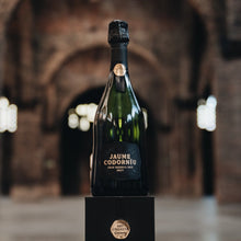 Load image into Gallery viewer, Bottle of Jáime Codorníu on a pedestal in an arched stone building.