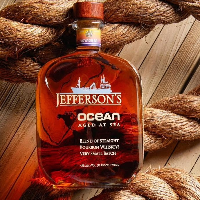 Load image into Gallery viewer, A bottle of Jefferson's Ocean Aged at Sea bourbon whiskey is displayed on a wooden surface, surrounded by thick natural rope.