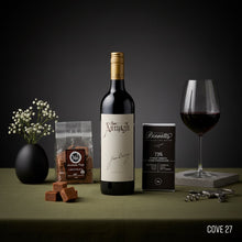 Load image into Gallery viewer, Jim Barry The Armagh Shiraz Wine bottle, glass, BENNETTS DARK chocolate, 36 Degrees chocolate fudge packet and flowers on a dark surface.