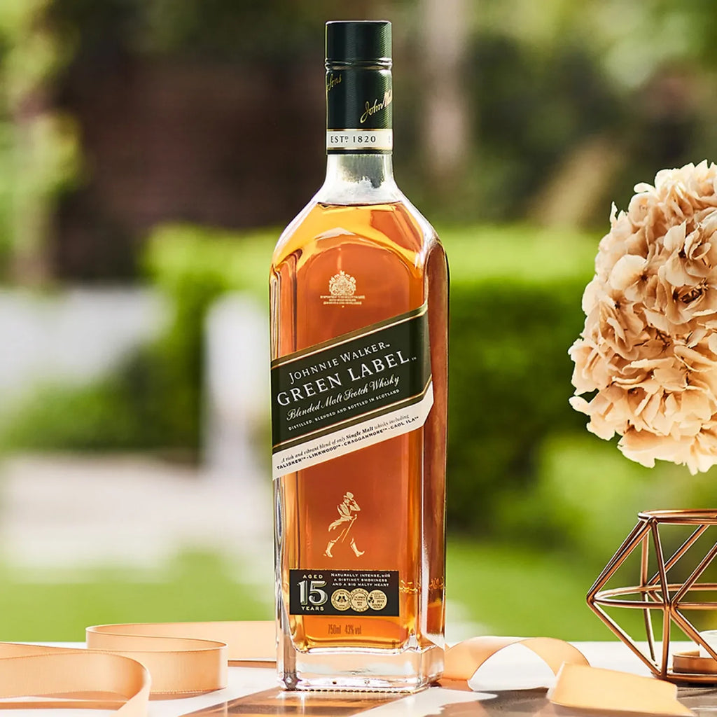 Johnnie Walker Green Label whisky bottle on a table with flowers and decor outdoors