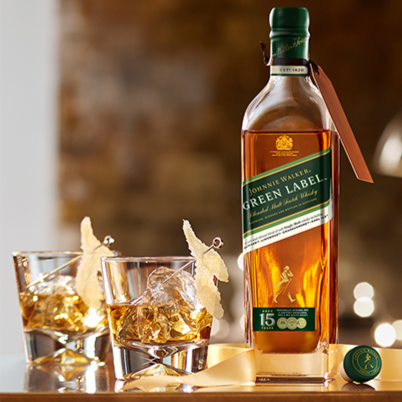Johnnie Walker Green Label bottle with glasses of whiskey on a wooden surface.