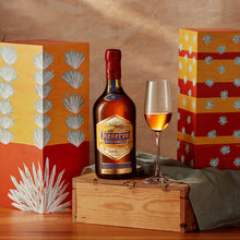 Load image into Gallery viewer, Bottle of Jose Cuervo Reserva De La Familia Tequila Extra Anejo on a wooden box, surrounded by decorative boxes.