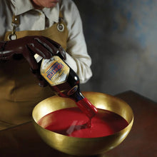 Load image into Gallery viewer, Person pouring red liquid from a bottle into a gold bowl.