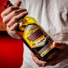Load image into Gallery viewer, Person holding a bottle of Jose Cuervo Reserva De La Familia Tequila Extra Anejo with a red background
