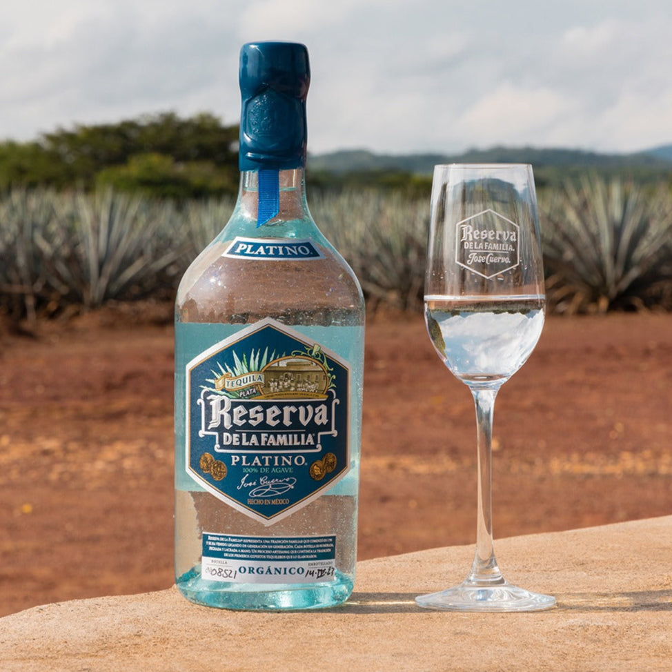 Bottle and glass of Reserva de la Familia tequila with agave plants in the background