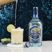 Load image into Gallery viewer, Reserva de la Familia Platino bottle with a cocktail and lime garnish on a dark textured background