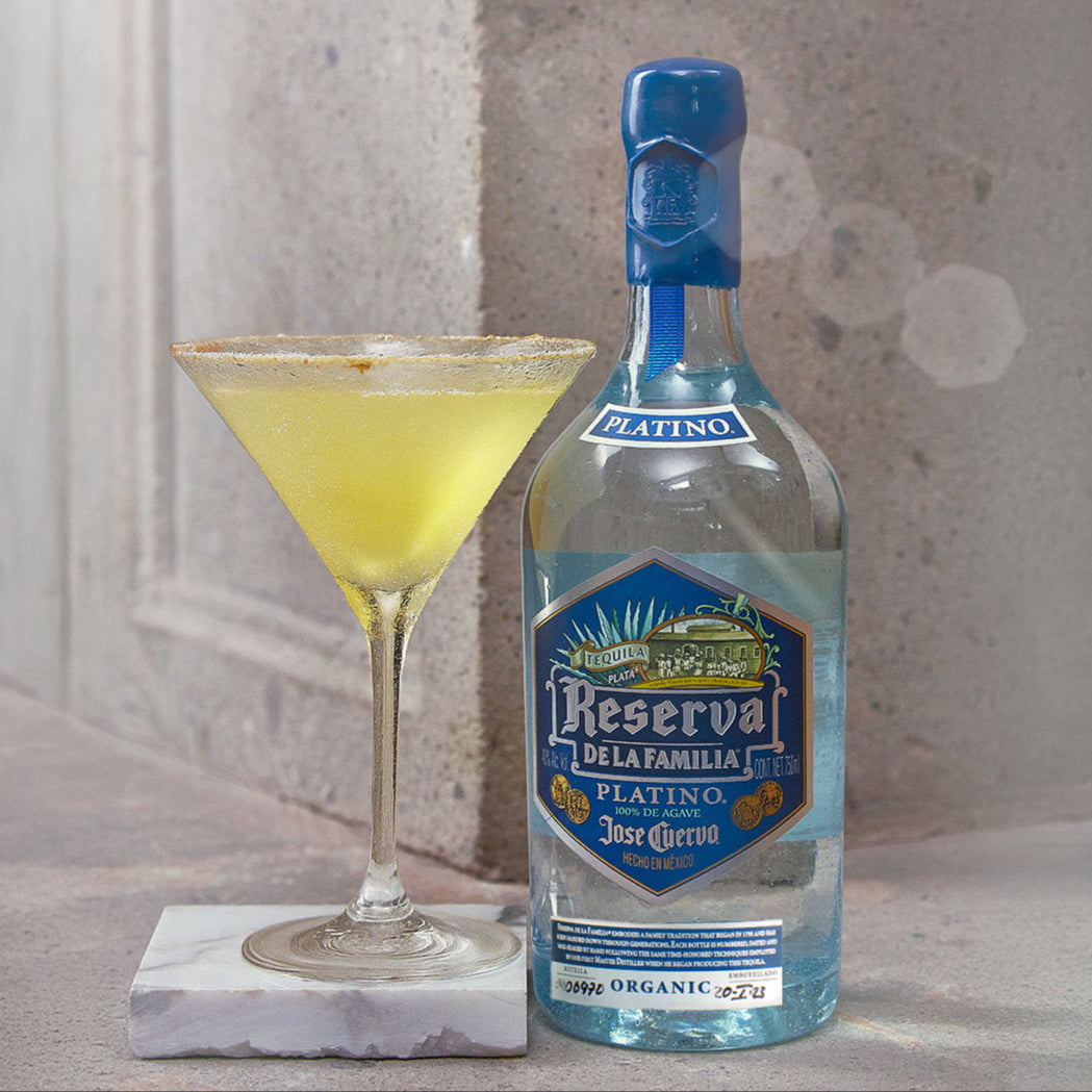 Load image into Gallery viewer, Bottle of Jose Cuervo Reserva de la Familia with a cocktail on a marble coaster against a textured wall.