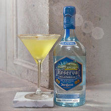 Load image into Gallery viewer, Bottle of Jose Cuervo Reserva de la Familia with a cocktail on a marble coaster against a textured wall.