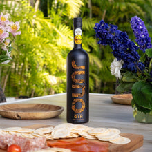 Load image into Gallery viewer, Bottle of Juno Fine Gin on a table with outdoor setting and flowers