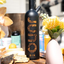 Load image into Gallery viewer, Juno Fine gin bottle with gold text on a blurred background