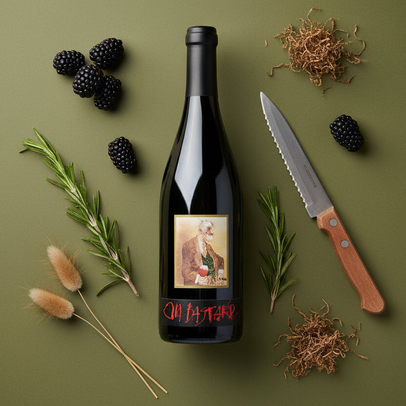 Kaesler_Old_Bastard_Shiraz wine bottle with label, knife, blackberries, and herbs on a green background