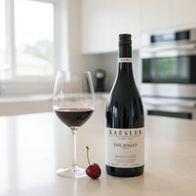Load image into Gallery viewer, Bottle of Kaesler The Bogan Shiraz wine with a glass and cherry on a kitchen counter