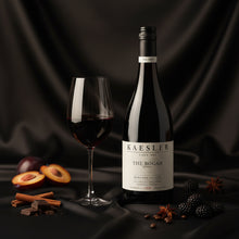 Load image into Gallery viewer, Bottle of Kaesler The Bogan Shiraz wine with a glass and fruit on a dark background