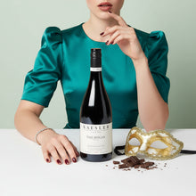 Load image into Gallery viewer, Woman in teal dress with a Kaesler The Bogan Shiraz wine bottle and mask on a light background