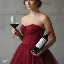 Load image into Gallery viewer, Woman in a red dress holding a wine glass and bottle of Kalleske Merchant Cabernet Sauvignon against a grey background