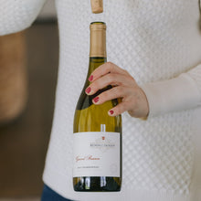 Load image into Gallery viewer, Woman holding a bottle of Kendall Jackson wine with a blurred background