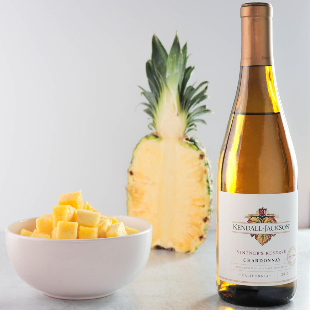 Bottle of Kendal Jackson Chardonnay with pineapple and mango on a light background