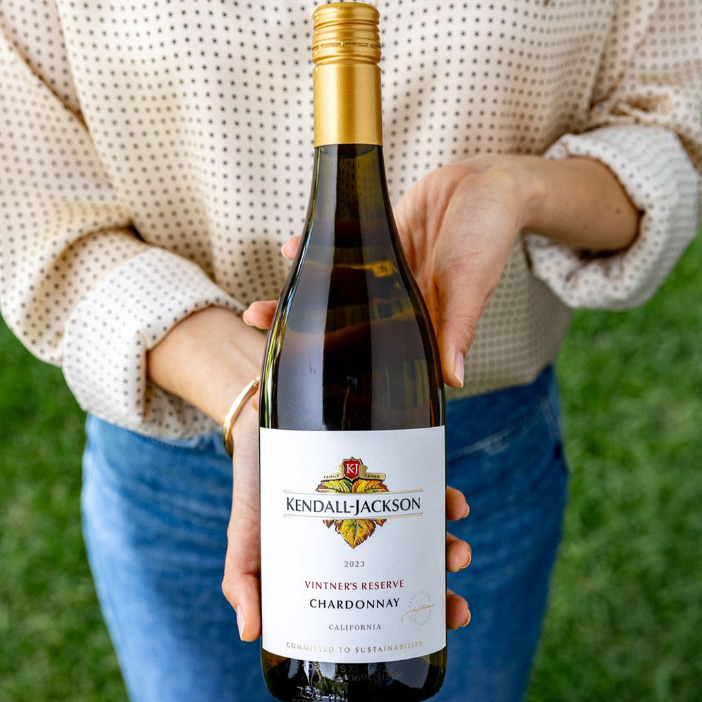 Woman holding a bottle of Kendall Jackson Vintner's Reserve Chardonnay against a grassy background