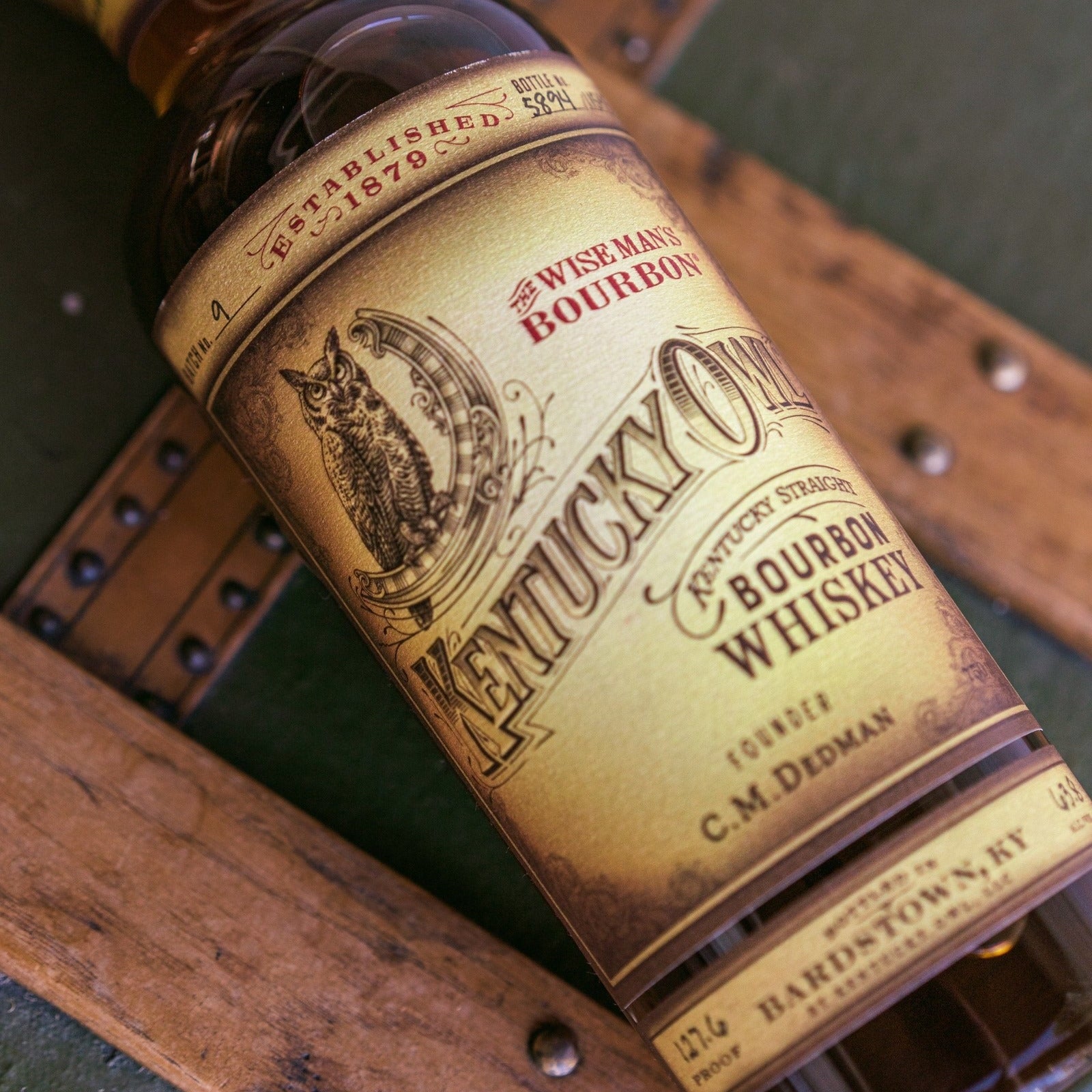 Load image into Gallery viewer, Bottle of Kentucky Owl bourbon whiskey labeled on a wooden surface.
