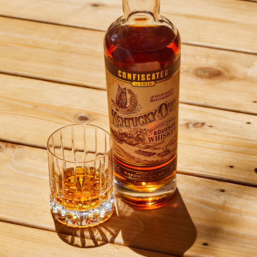 Load image into Gallery viewer, Bottle and glass of Kentucky bourbon whiskey on a wooden table.