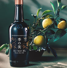 Load image into Gallery viewer, Bottle of KI NO BI Kyoto Dry Gin with a branch of lemons and leaves on a textured surface.