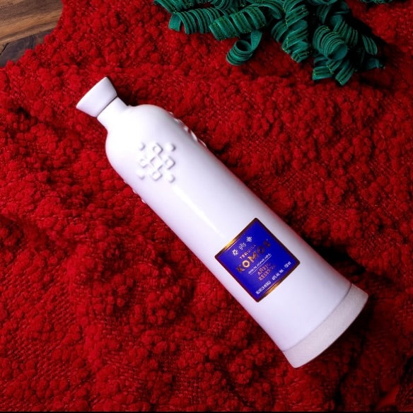 Load image into Gallery viewer, Komos Reposado Rosa Tequila bottle lying on a red textured surface