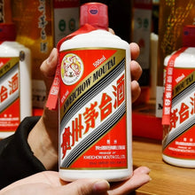 Load image into Gallery viewer, Person holding a bottle of Moutai liquor with more bottles in the background.
