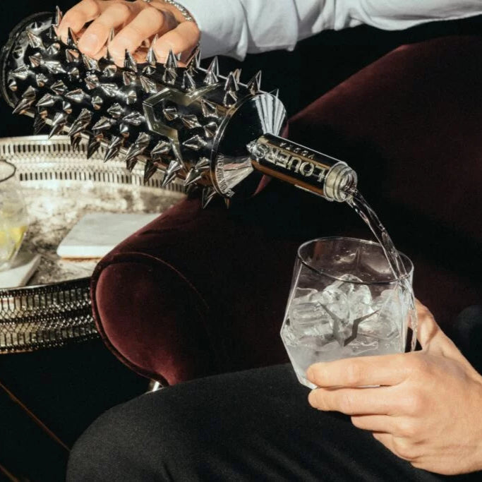 Load image into Gallery viewer, Person pouring a Louers vodka from a spiky bottle into a glass with ice.