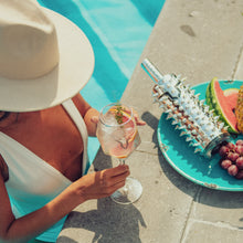 Load image into Gallery viewer, An image of a woman in a pool drinking an inviting cocktail next to a bottle LOUERS vodka at the side of the pool