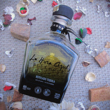 Load image into Gallery viewer, La-Hora-Azul-Blue-Hour-Reposado-Tequila bottle with decorative elements on a textured surface