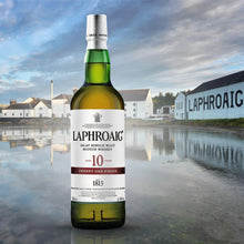 Load image into Gallery viewer, Laphroaig whisky bottle with a scenic background featuring a distillery.