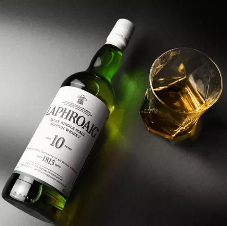 Bottle of Laphroaig 10-year-old whisky with a glass on a dark background