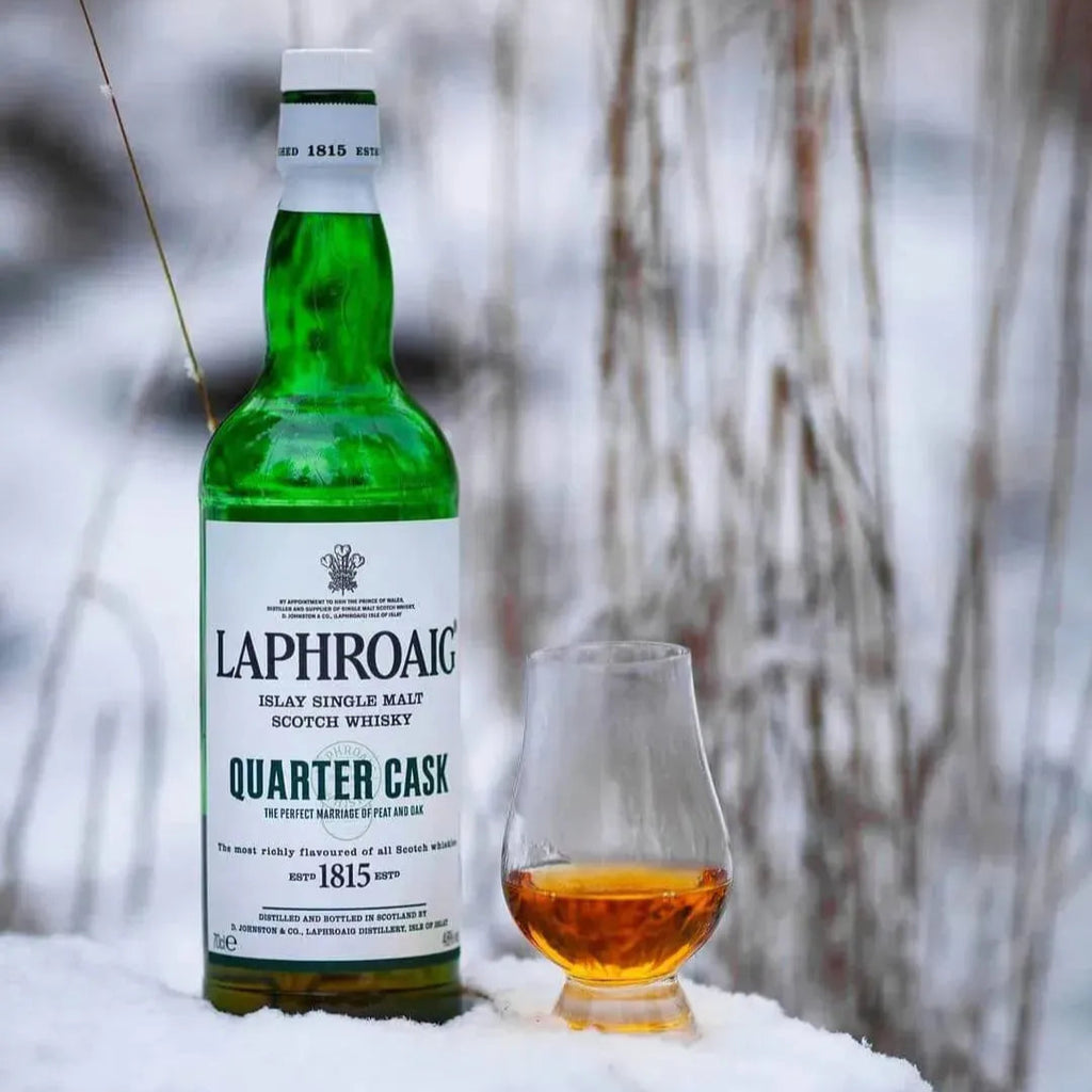 Laphroaig quarter cask whisky bottle and glass in the snow