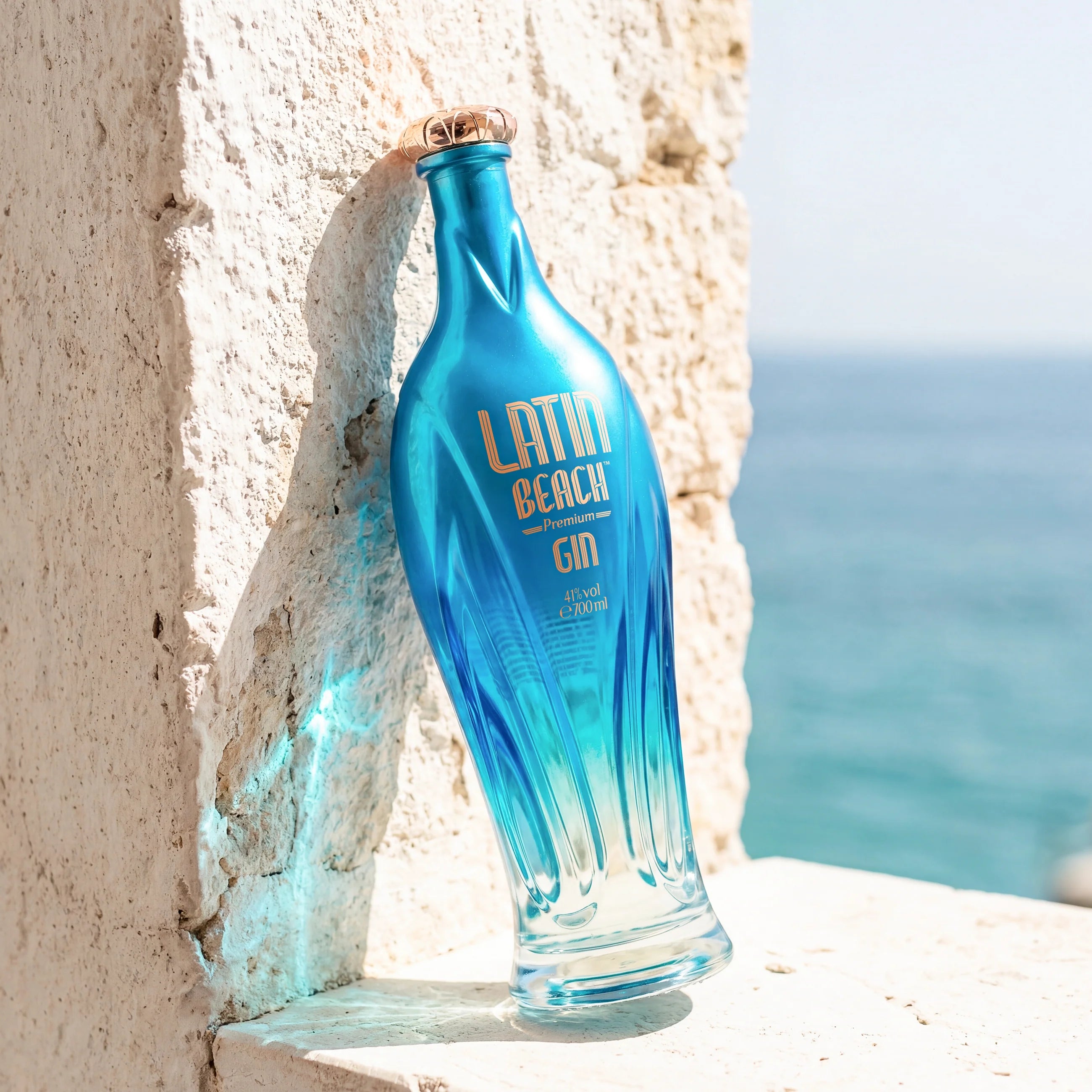 Load image into Gallery viewer, Blue bottle of Latin Beach Gin against a stone wall with Amalfi Coast ocean view