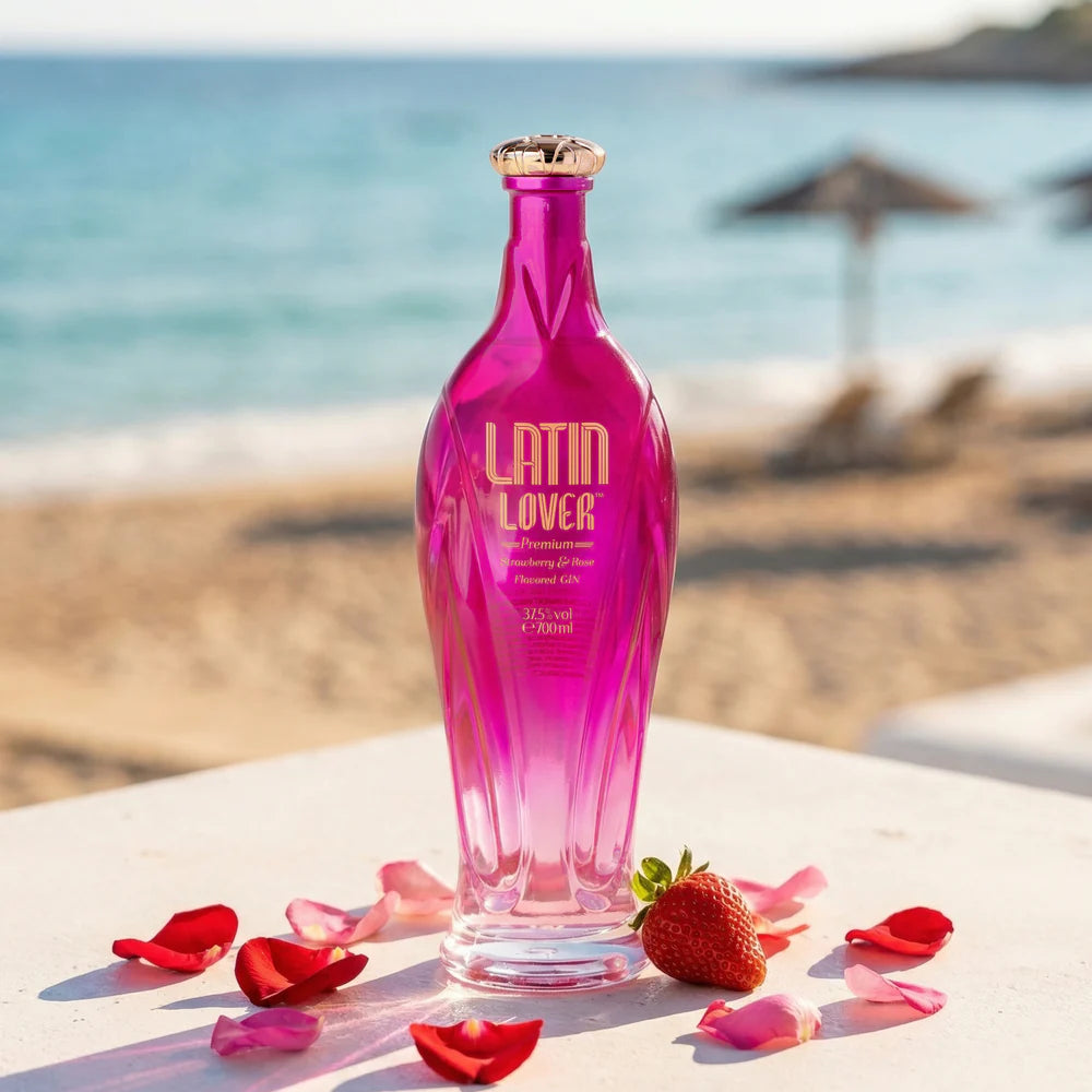 Load image into Gallery viewer, Pink Latin Lover Gin bottle on a beach with flowers and a strawberry.
