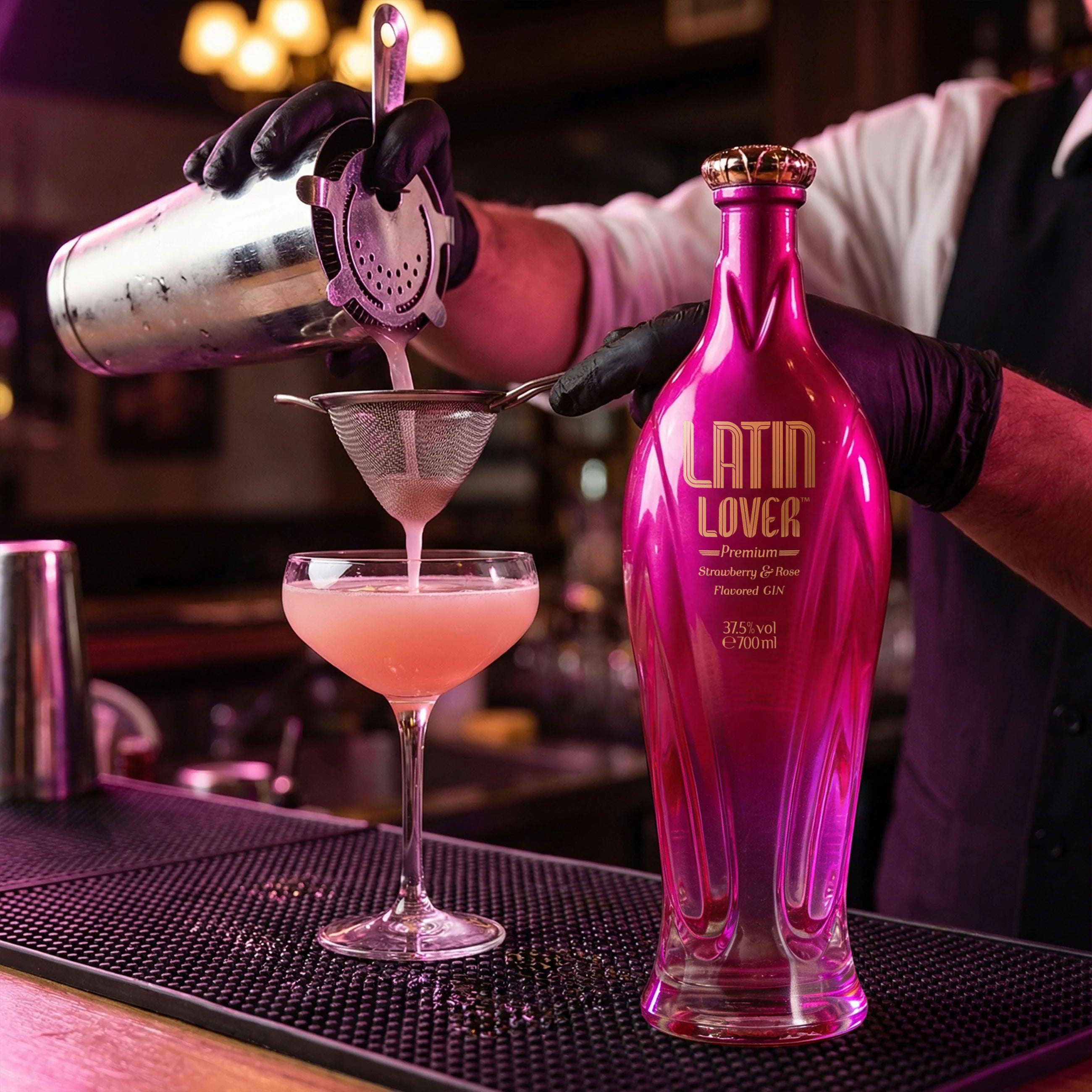 Load image into Gallery viewer, Barman pouring a pink cocktail into a glass with a Latin Lover Gin bottle in the foreground.