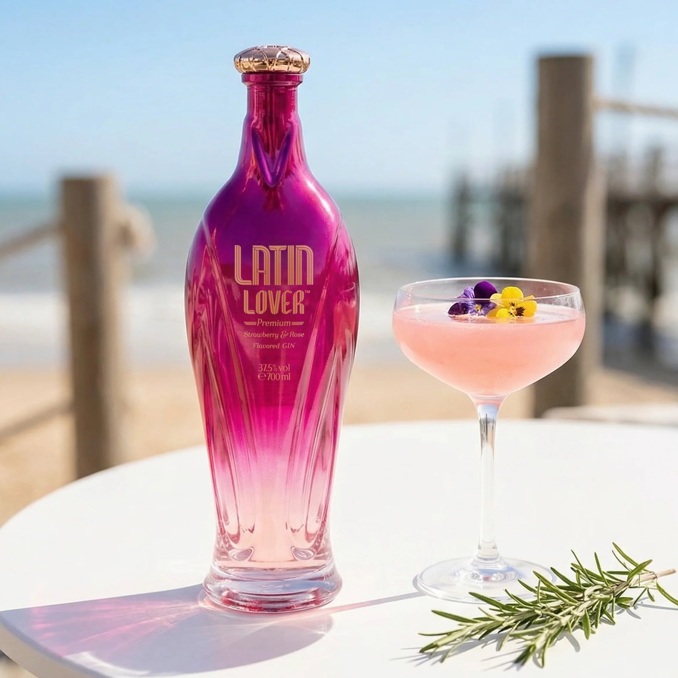 Load image into Gallery viewer, Pink Latin Lover Gin bottle next to a cocktail on a table with a beach background