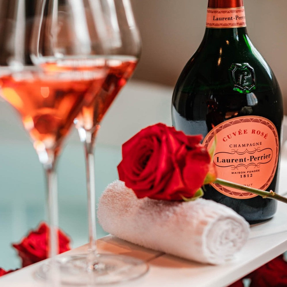 Load image into Gallery viewer, A bottle of Laurent-Perrier Rosé and two glasses and a red rose on a marble table 