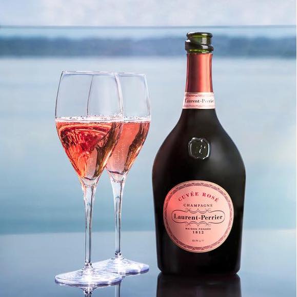 Load image into Gallery viewer, A bottle of Laurent-Perrier Rosé and two glasses with a blurry blue background