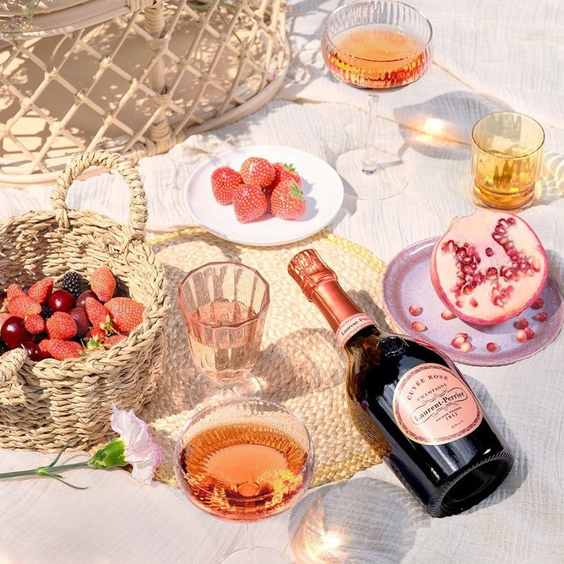 Load image into Gallery viewer, A bottle of Laurent-Perrier Rosé on a pic nic blanket with lots of fruit and glasses full of champagne