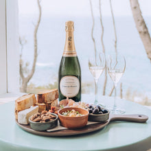 Load image into Gallery viewer, Bottle of Laurent-Perrier champagne with a charcuterie board on a table by a window.