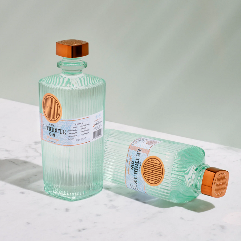 Two bottles of Le Tribute Gin on a white marble surface