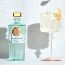 Load image into Gallery viewer, Bottle of Le Tribute Gin with a cocktail garnished with a lemon twist on a light background