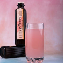 Load image into Gallery viewer, Bottle of Le Tribute Pink Grapefruit Tonic Water  with a glass of pink liquid on a pink background