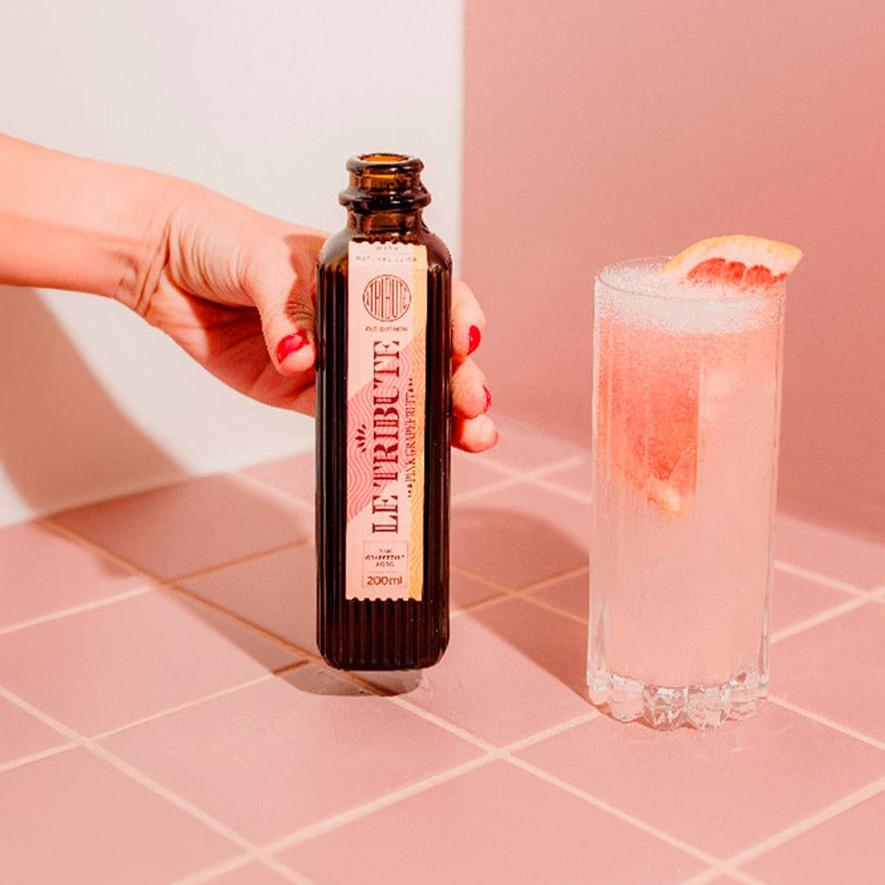 Load image into Gallery viewer, Bottle of Le Tribute Pink Grapefruit Tonic Water  with a cocktail on a pink tiled surface, featuring awards text.