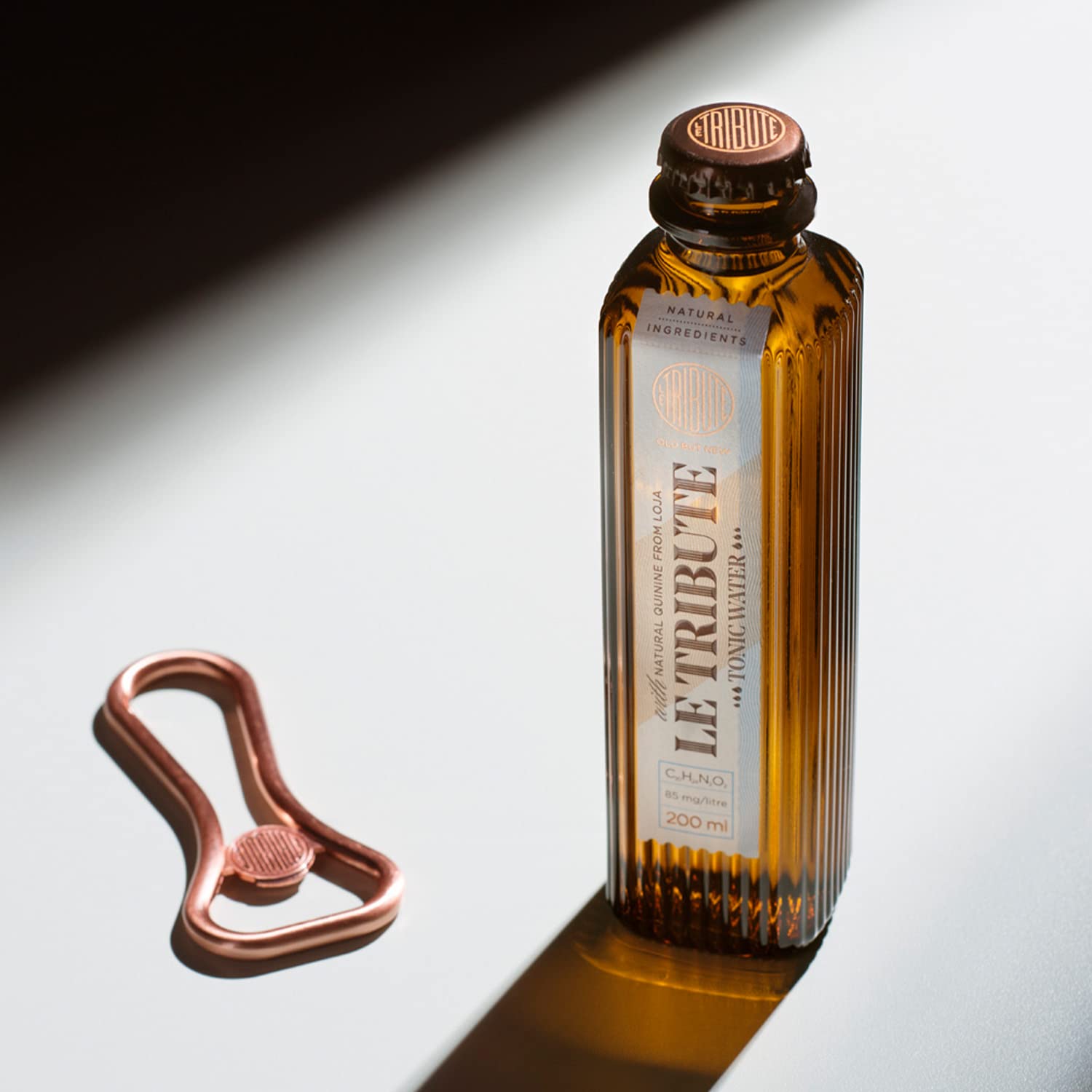 Load image into Gallery viewer, Bottle of Le Tribute Tonic Water and bottle opener on a reflective surface