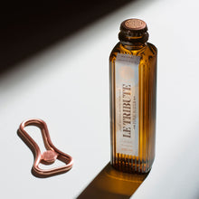 Load image into Gallery viewer, Bottle of Le Tribute Tonic Water and bottle opener on a reflective surface