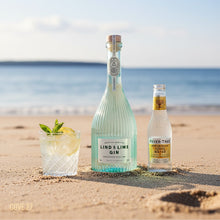 Load image into Gallery viewer, Bottle of Lind &amp; Lime Gin and Fever-Tree Tonic Water on a beach with a glass of gin and tonic.